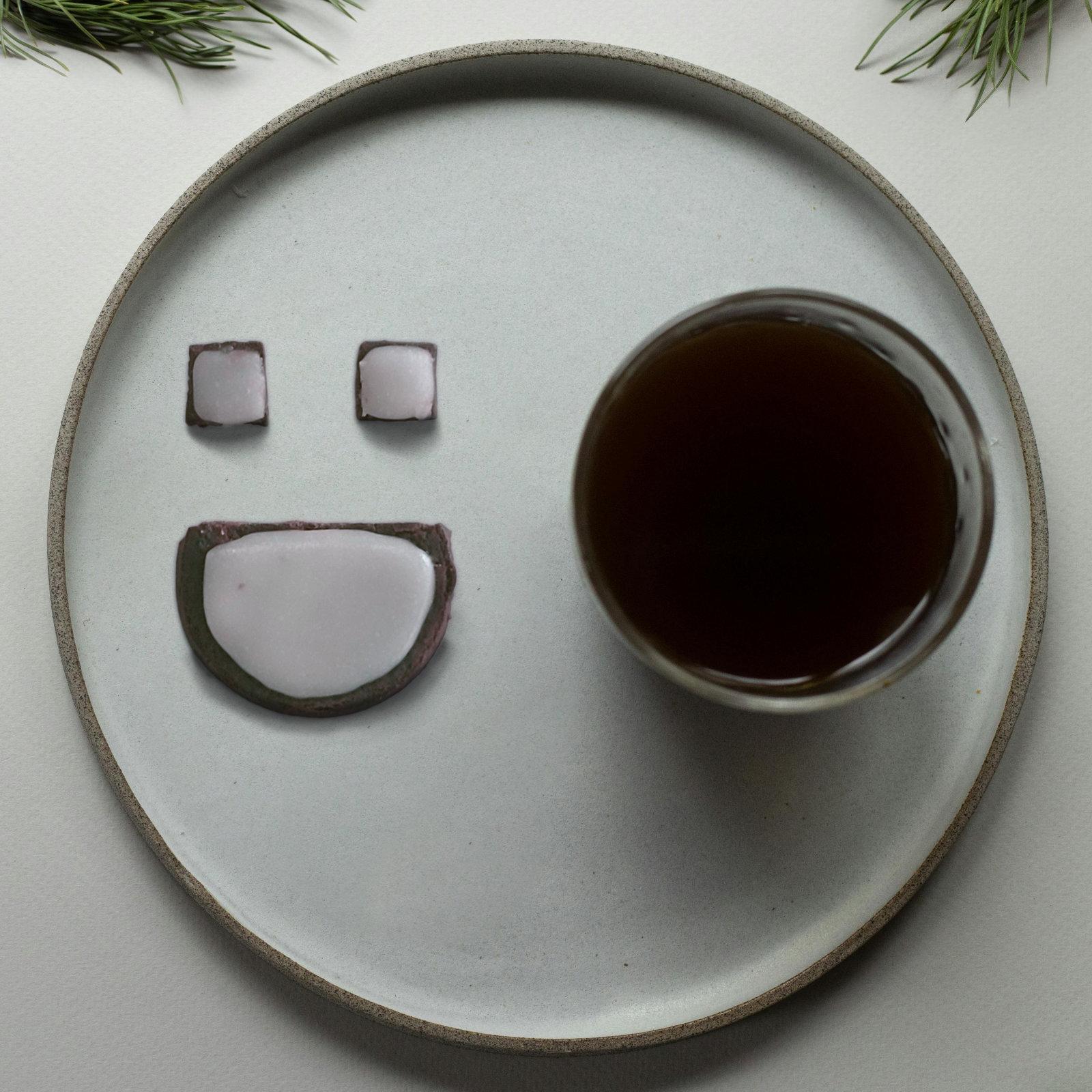 Artwork for Same Day Shipping by dot.darkness. A light gray plate on a white table contains a glass with a dark liquid,coffee or hot chocolate perhaps, and a chocolate cookie in the shape of the dot.darkness logo to the left of it. "Same Day Shipping" is written in a green script at the top of the plate.